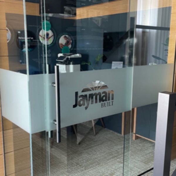 A glass door with Jayman Built's logo on a frosted strip background.