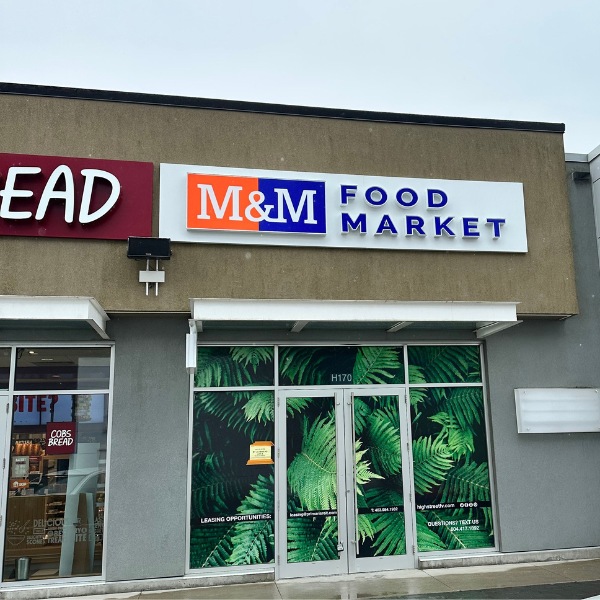 M&M Food Market sign on a building in blue and orange with a white background.